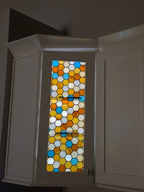 Honeycomb stained glass cabinet insert glowing gold and blue